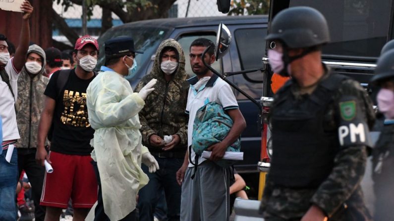 Los migrantes hondureños deportados desde México, reciben instrucciones de la policía antes de ser puestos en cuarentena para evitar la propagación del COVID-19, a su llegada al aeropuerto internacional de Toncontin en Tegucigalpa (Honduras), el 14 de abril de 2020. (ORLANDO SIERRA/AFP vía Getty Images)