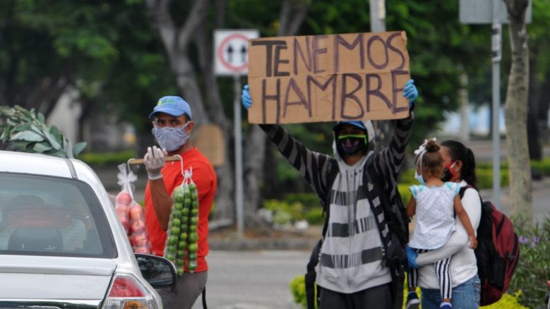 Un migrante venezolano sostiene un letrero que dice "Tenemos hambre" en las calles de Guayaquil, Ecuador, el 22 de abril de 2020, durante la pandemia de COVID-19. (JOSE SANCHEZ/AFP vía Getty Images)