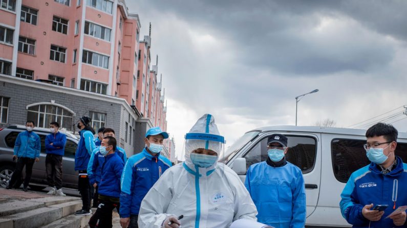 Un trabajador médico revisa notas frente a los empleados de la entrega de alimentos, en la fila para hacer la prueba de ácido nucleico como parte de las medidas contra la pandemia del COVID-19, en un centro de servicios de salud en Suifenhe, en la provincia nororiental de Heilongjiang de China. (STR/AFP vía Getty Images)