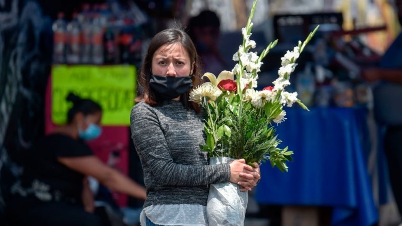 Una familiar de una persona fallecida permanece en la entrada del panteón de Iztapalapa ya que la entrada está restringida en medio de la nueva pandemia del virus del PCCh, en la Ciudad de México (México) el 29 de abril de 2020. (PEDRO PARDO/AFP vía Getty Images)