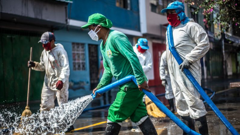 Trabajadores municipales limpian y desinfectan los alrededores del mercado de la Caquetá en el norte de Lima (Perú) el 30 de abril de 2020 en medio del brote del virus del PCCh. (ERNESTO BENAVIDES/AFP vía Getty Images)