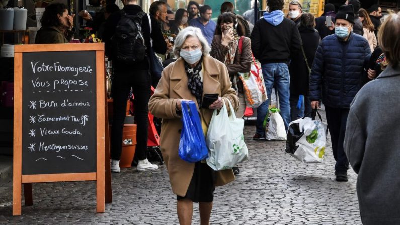 Una mujer con una mascarilla protectora camina por la calle Aligre mientras hace sus compras en el mercado de alimentos, el 2 de mayo de 2020 en París (Francia). (Alain Jocard/AFP vía Getty Images)