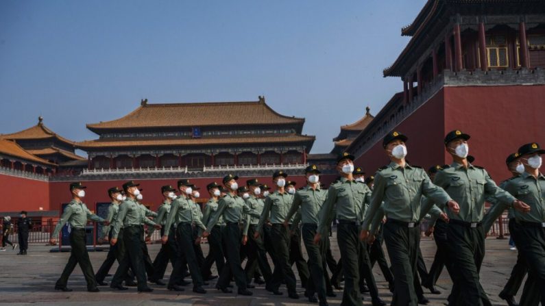 La policía paramilitar china con mascarillas protectoras mientras marchan junto a la entrada de la Ciudad Prohibida, ya que reabrió a visitantes limitados para las vacaciones de mayo, el 2 de mayo de 2020 en Beijing, China. (Kevin Frayer/Getty Images)