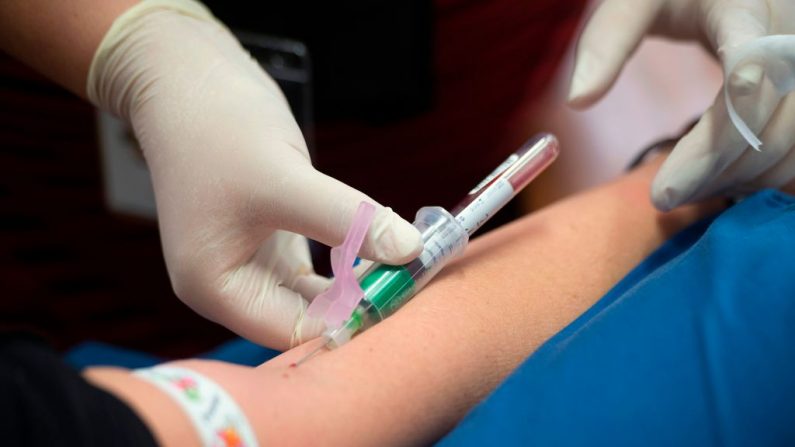A un voluntario se le extrae sangre mientras espera a ser inyectado para un ensayo clínico en Ciudad del Cabo de una vacuna que podría ayudar a limitar los daños causados por COVID-19, el 4 de mayo de 2020. (RODGER BOSCH / AFP vía Getty Images)