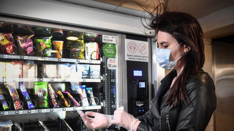 Una mujer compra una mascarilla y guantes en una máquina expendedora en el metro de Moscú (Rusia) el 5 de mayo de 2020, en medio de la propagación de COVID-19. (ALEXANDER NEMENOV/AFP vía Getty Images)