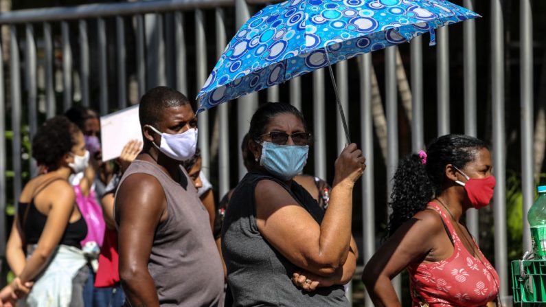 La gente que usa máscara protectora espera en la fila frente a una sucursal del banco federal Caixa Economica en el barrio de Alcántara para recibir el beneficio urgente del gobierno en medio de la pandemia del virus del PCCh el 05 de mayo de 2020 en Sao Goncalo, Brasil. (Luis Alvarenga/Getty Images)