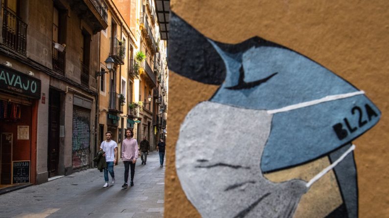 Dos personas pasan por delante de un grafiti que ilustra una mascarilla el 12 de marzo de 2020 en Barcelona, España. (Foto de David Ramos/Getty Images)
