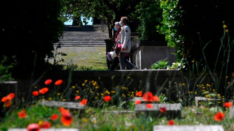 Las mujeres caminan en el cementerio de Verano el 7 de mayo de 2020 en Roma, Italia, durante el encierro del país para frenar la propagación de la infección COVID-19, causada por el virus del PCCh. (FILIPPO MONTEFORTE/AFP vía Getty Images)