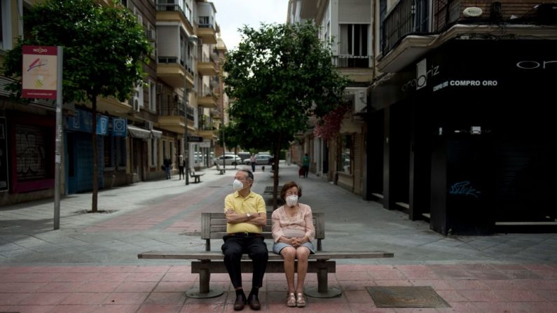 Una pareja de ancianos con máscaras faciales se sienta en un banco de Sevilla (España) el 7 de mayo de 2020, mientras el país se prepara para suavizar sus duras medidas de encierro para evitar la propagación del virus del PCCh. (CRISTINA QUICLER/AFP vía Getty Images)