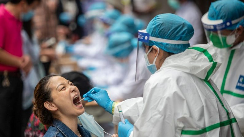 Un trabajador médico toma una muestra de hisopado de una residente para analizar el virus del PCCh en Wuhan, China, el 15 de mayo de 2020. (STR/AFP a través de Getty Images)
