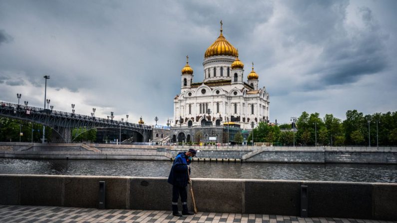 Un trabajador municipal limpia el terraplén del río Moskva cerca de la catedral de Cristo Salvador en el centro de Moscú (Rusia) el 16 de mayo de 2020 en medio de la propagación de la pandemia COVID-19 causada por el virus del PCCh. (DIMITAR DILKOFF/AFP vía Getty Images)