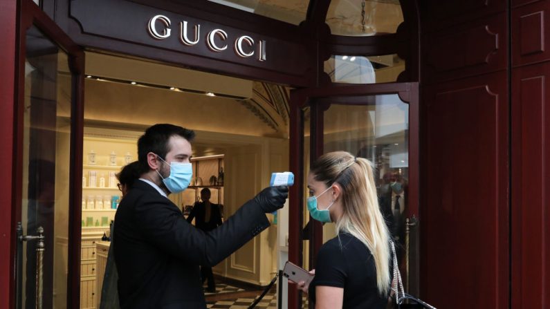 Un empleado de Gucci toma la temperatura a una clienta en la entrada de la tienda el 18 de mayo de 2020 en Roma, Italia. (Marco Di Lauro/Getty Images)
