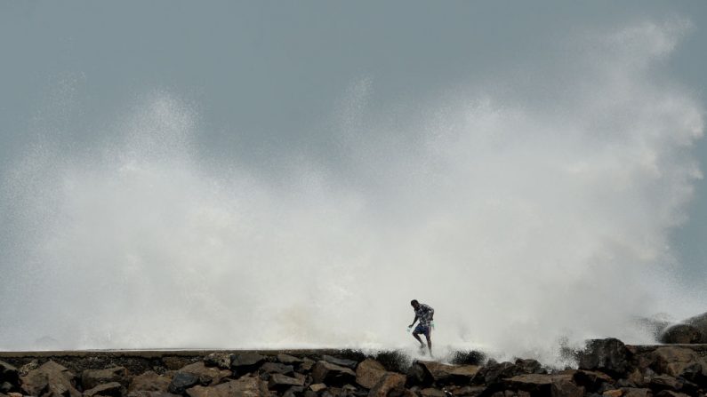 Un hombre pasa mientras las olas golpean un rompeolas en el puerto pesquero de Kasimedu en Chennai el 19 de mayo de 2020, mientras el superciclón Amphan se dirige hacia la costa oriental de India. (ARUN SANKAR/AFP vía Getty Images)
