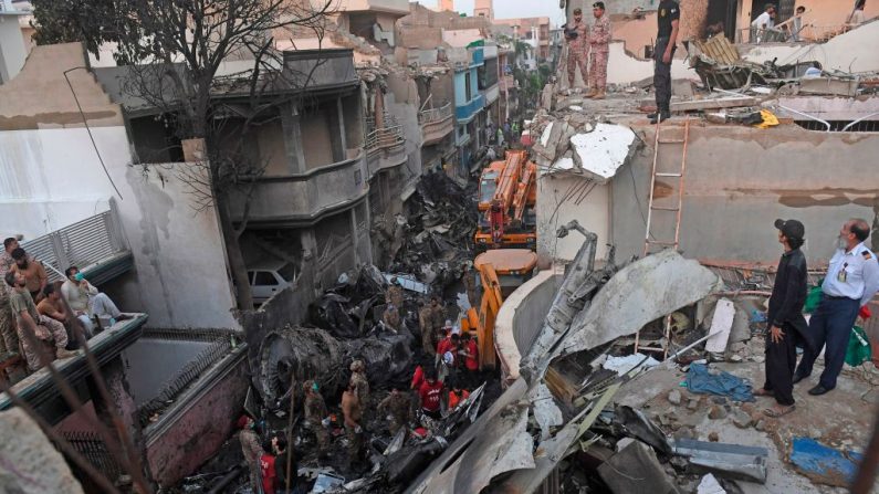 Personal de seguridad busca víctimas en los restos de un avión de Pakistan International Airlines después de que se estrellara en una zona residencial de Karachi el 22 de mayo de 2020. (ASIF HASSAN / AFP vía Getty Images)