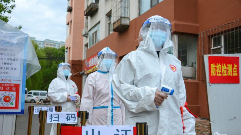 Personal espera para verificar el permiso de entrada de las personas, controlar su temperatura corporal y escanear sus códigos de salud en la entrada de un complejo residencial en la ciudad de Jilin, China, el 25 de mayo de 2020. (STR/AFP a través de Getty Images)