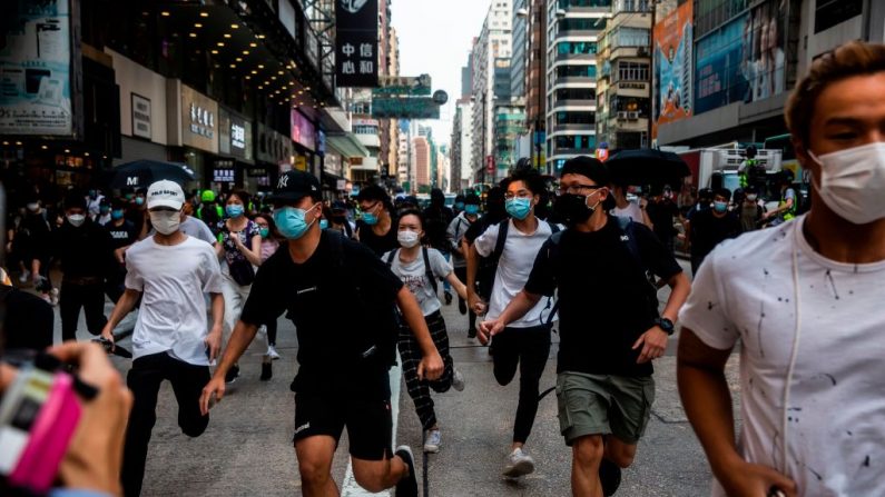 Manifestantes prodemocracia de Hong Kong corren cuando la policía llega para despejar una carretera que estaban ocupando durante una protesta en el distrito de Mongkok el 27 de mayo de 2020. (ISAAC LAWRENCE/AFP vía Getty Images)