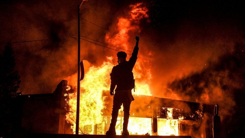 Un manifestante reacciona frente a un edificio en llamas, incendiado durante una manifestación en Minneapolis, Minnesota, el 29 de mayo de 2020, por la muerte de George Floyd, un hombre negro que murió después de que un policía blanco se arrodillara en su cuello durante varios minutos. (CHANDAN KHANNA/AFP a través de Getty Images)
