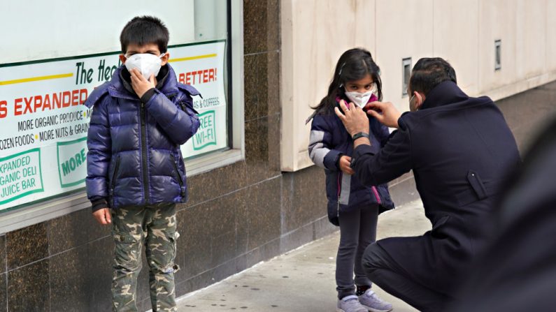 NUEVA YORK, NUEVA YORK - ABRIL 05: Un hombre ajusta la máscara protectora de un niño en medio de la pandemia del COVID-19 el 05 de abril de 2020 en la ciudad de Nueva York. (Foto de Cindy Ord/Getty Images)
