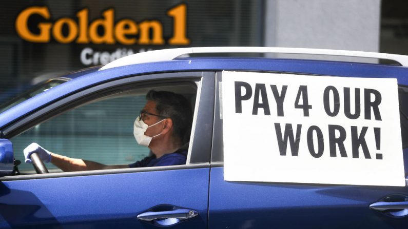 Un conductor usa una máscara facial y guantes durante una protesta en una caravana, en California por la ley AB5, en Los Ángeles el 16 de abril de 2020. (Mario Tama / Getty Images)
