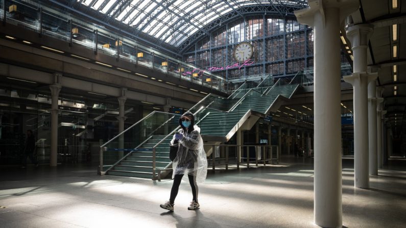 Una mujer lleva una máscara protectora y un protector de lluvia de plástico mientras espera tren en la estación internacional de St. Pancras el 4 de mayo de 2020 en Londres, Inglaterra. (Leon Neal/Getty Images)