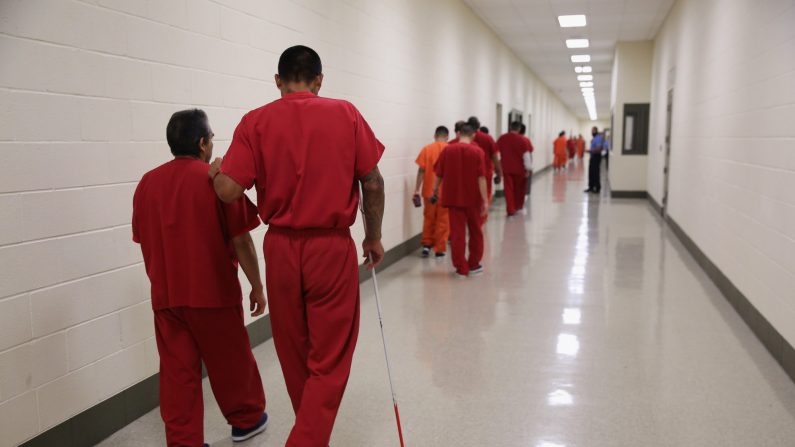 Un detenido ciego camina con un compañero inmigrante en el centro de detención de Adelanto el 15 de noviembre de 2013 en Adelanto, California. (John Moore/Getty Images)