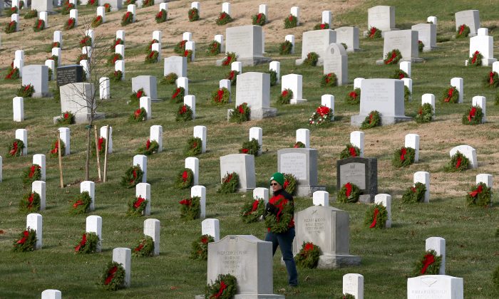 Un voluntario busca una tumba para colocar una corona durante el Día Nacional de las Coronas de América en el Cementerio Nacional de Arlington, Va., el 13 de diciembre de 2014. (Mark Wilson/Getty Images)