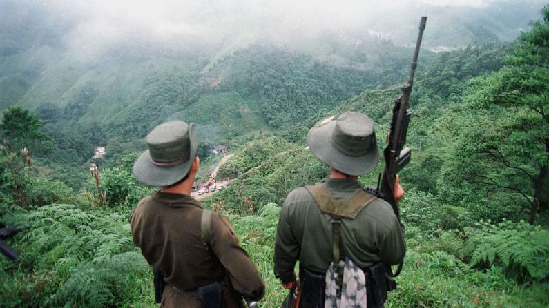 Dos soldados armados pertenecientes a las Fuerzas Armadas Revolucionarias de Colombia (FARC) vigilan el paso de Berlín, el 7 de marzo, cerca de Florencia, en la provincia sureña de Caquetá, en Colombia. (Pedro Uguarte/AFP vía Getty Images)
