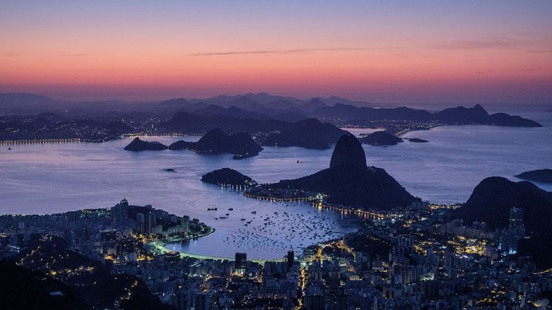 TOPSHOT - Una vista general tomada desde el cerro Corcovado muestra el monte Pan de Azúcar y la bahía de Guanabara antes del amanecer del 5 de agosto de 2016 en Río de Janeiro. (YASUYOSHI CHIBA/AFP a través de Getty Images)
