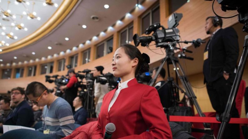 Un asistente sostiene un micrófono para que los periodistas lo usen durante una conferencia de prensa del Ministro de Finanzas chino Xiao Jie en Beijing el 7 de marzo de 2018. (NICOLAS ASFOURI/AFP a través de Getty Images)