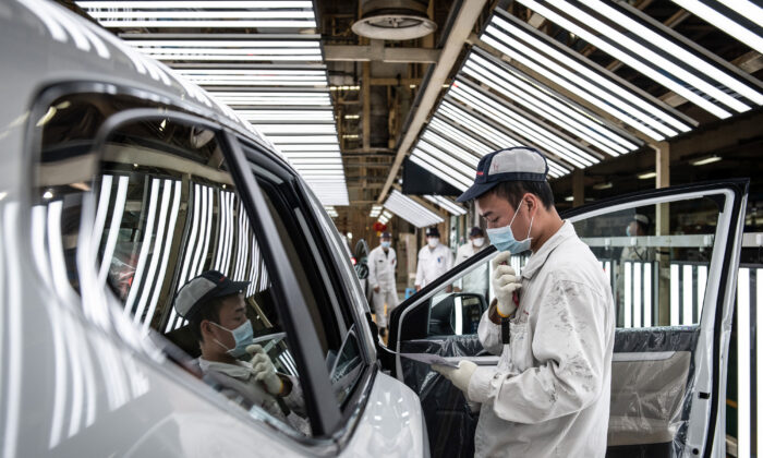 Un empleado con mascarilla trabaja en una línea de ensamblaje en una planta automotriz de Dongfeng Honda en la ciudad de Wuhan, provincia de Hubei, China, el 7 de abril de 2020. (Foto de STR / AFP a través de Getty Images)