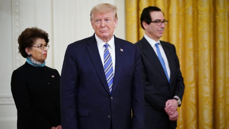 El presidente Donald Trump está flanqueado por la administradora de la SBA Jovita Carranza (I) y el secretario del Tesoro Steven Mnuchin, en una sesión informativa en la Casa Blanca en Washington, el 28 de abril de 2020. (Mandel Ngan/AFP/Getty Images)