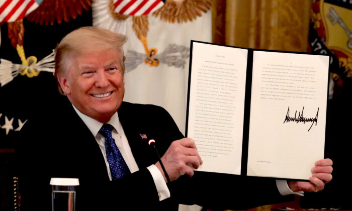 El presidente de Estados Unidos, Donald Trump, sostiene una copia de una orden ejecutiva que firmó sobre una orden de desregulación, durante una reunión con su gabinete en la Sala Este de la Casa Blanca el 19 de mayo de 2020. (Alex Wong/Getty Images)