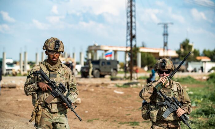 Un soldado estadounidense usa un transceptor de radio portátil mientras está parado junto a otro militar, cerca de la aldea de Tannuriyah,  en el noreste de Siria, el 2 de mayo de 2020. (Delil Souleiman/AFP/Getty Images)
 
