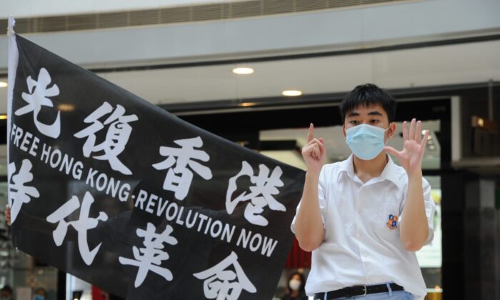 Un manifestante permanece junto a una bandera con las palabras "Liberen Hong Kong, Revolución Ahora" durante una protesta en el centro comercial IFC de Hong Kong el 29 de mayo de 2020. (Song Bilung/The Epoch Times)