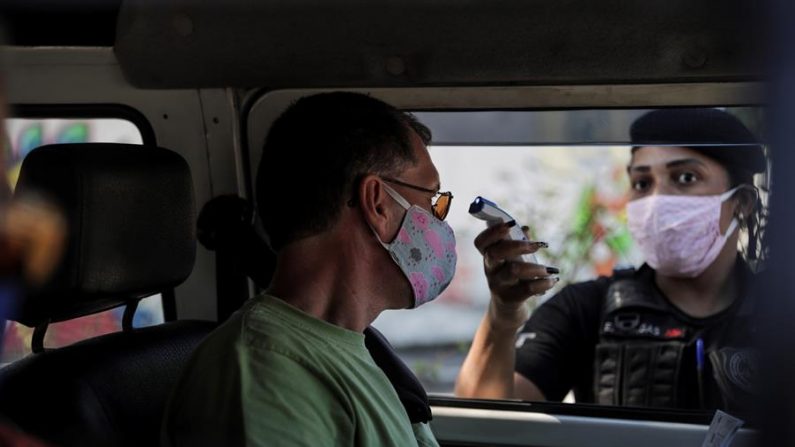 Un agente de seguridad del ayuntamiento de la ciudad de Niterói toma la temperatura de un hombre en Niterói, Río de Janeiro (Brasil). EFE/Antonio Lacerda/Archivo
