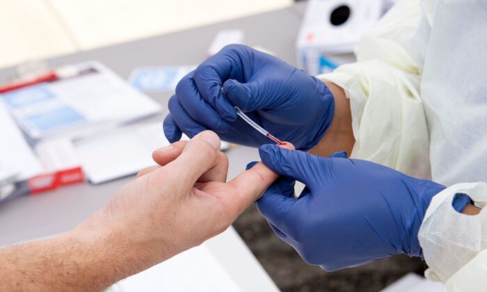 Un trabajador de la salud toma una gota de sangre para una prueba de anticuerpos COVID-19 en Torrance, California, el 5 de mayo de 2020. (Valerie Macon/AFP/Getty Images)