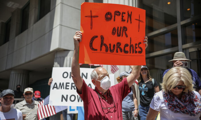 Manifestantes con carteles exigiendo la reapertura de su iglesia, protestan durante una manifestación para reabrir California y contra las directivas de confinamiento, en San Diego, California, el 1 de mayo de 2020. (Sandy Huffaker/AFP a través de Getty Images)
 

 
