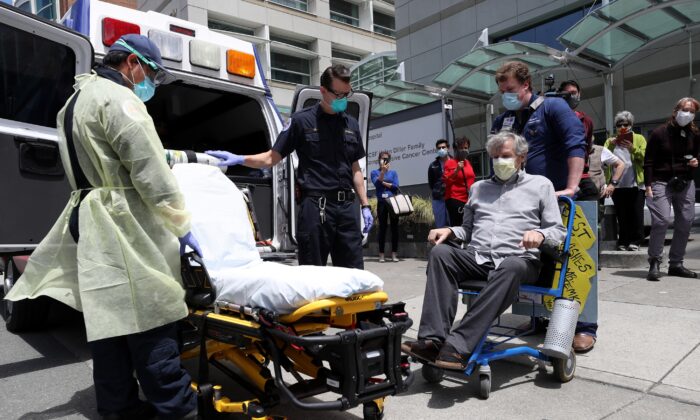 Ronald Temko, sentado, un paciente de COVID-19, se prepara para ser cargado en una ambulancia después del alta del Centro Médico UCSF en Mount Zion en San Francisco, California, el 20 de mayo de 2020. (Justin Sullivan / Getty Images)