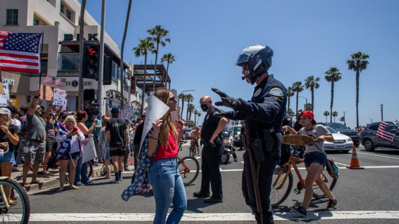 Un oficial de policía habla con un manifestante en una protestas en Huntington Beach, California, el 1 de mayo de 2020. (Apu Gomes/Getty Images)
