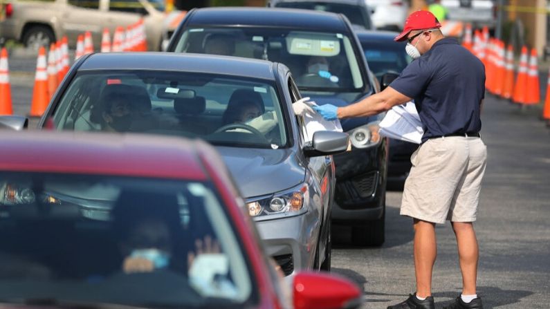 Miguel Díaz, que trabaja para la ciudad de Hialeah, entrega solicitudes de desempleo a personas en sus vehículos frente a la biblioteca John F. Kennedy el 8 de abril de 2020 en Hialeah, Florida.  (Joe Raedle/Getty Images)