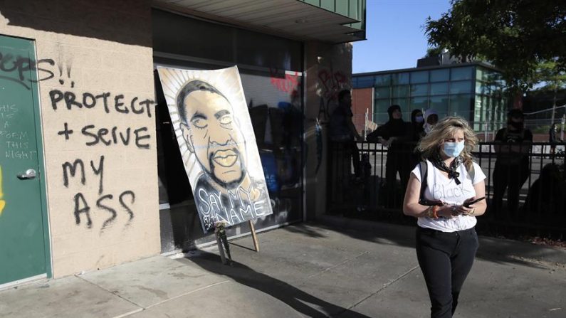 La gente ve un cuadro de George Floyd durante el quinto día de protestas por el arresto de George Floyd, que luego murió bajo custodia policial, en Minneapolis, Minnesota (EE.UU.), el 30 de mayo de 2020. EFE/EPA/TANNEN MAURY
