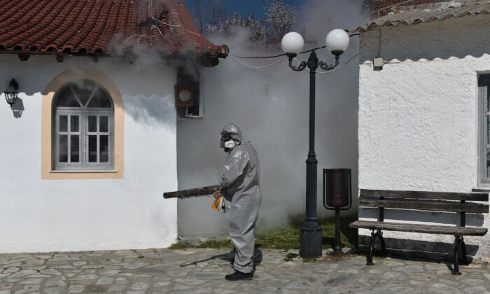 Un trabajador utiliza un nebulizador térmico para desinfectar fuera de una iglesia en Salónica, Grecia, el 12 de marzo de 2020. (Sakis Mitrolidis / AFP / Getty Images)