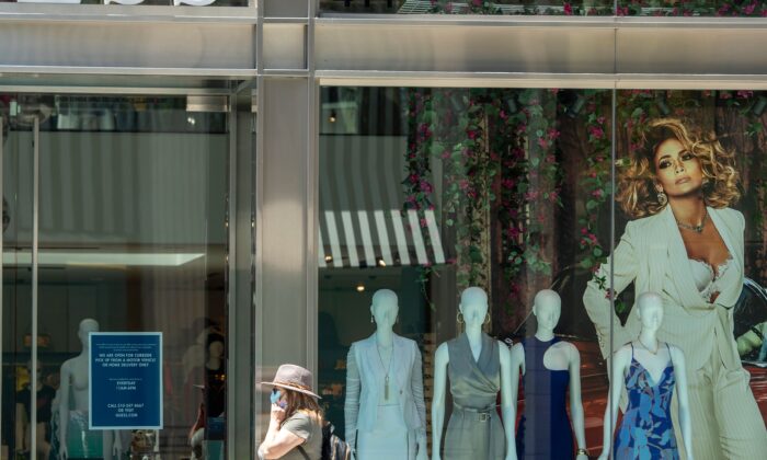 Una mujer con mascarilla camina frente una tienda Guess en Beverly Hills, California, el 26 de mayo de 2020 (Valerie Macon/AFP via Getty Images)