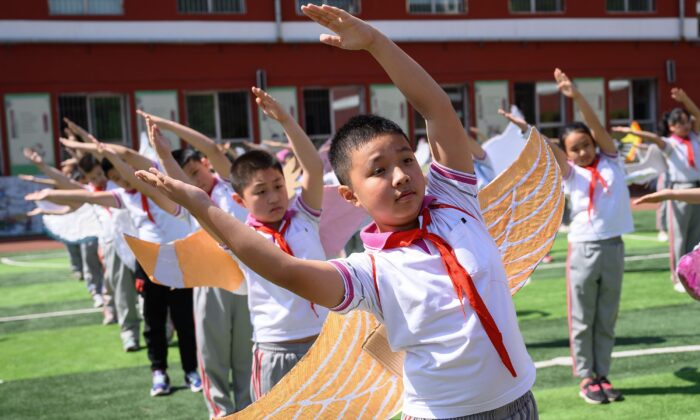 Estudiantes de escuela primaria llevan alas para mantener el distanciamiento social en un patio de recreo en Taiyuan, en la provincia norteña china de Shanxi, el 20 de mayo de 2020. (STR/AFP vía Getty Images)