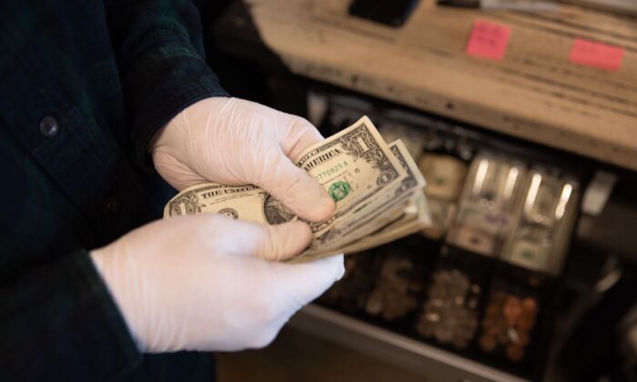 Trabajador cuenta dinero con guantes protectores en la cafetería del Almacén 4 en Vandalia, Ohio, el 15 de marzo de 2020. (Brad Lee/AFP vía Getty Images)
