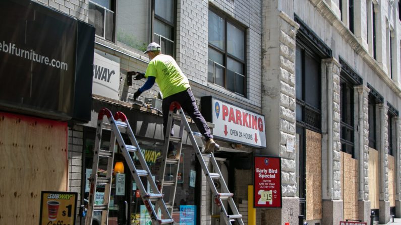 Un trabajador de construcción arregla el letrero de una tienda en Manhattan, Nueva York, el 9 de junio de 2020. (Chung I Ho/The Epoch Times)