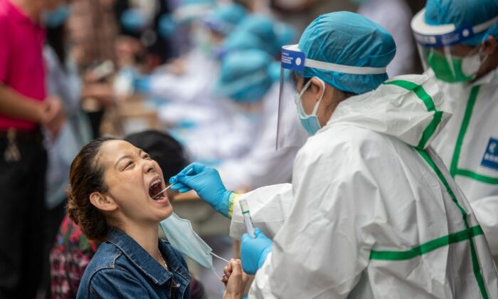 Un trabajador médico toma una muestra de hisopo de un residente para analizar el virus del PCCh en Wuhan, China, el 15 de mayo de 2020. (STR/AFP a través de Getty Images)