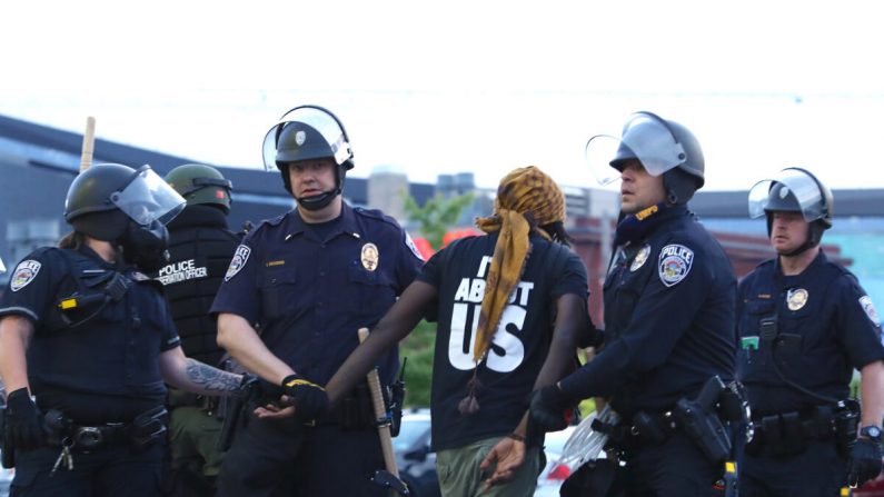 La policía estatal detiene a un manifestante después de permanecer fuera del toque de queda a las 8 pm del gobernador durante la sexta noche de protestas y violencia tras la muerte de George Floyd, en Minneapolis, Minnesota, el 31 de mayo de 2020. (Charlotte Cuthbertson/The Epoch Times)