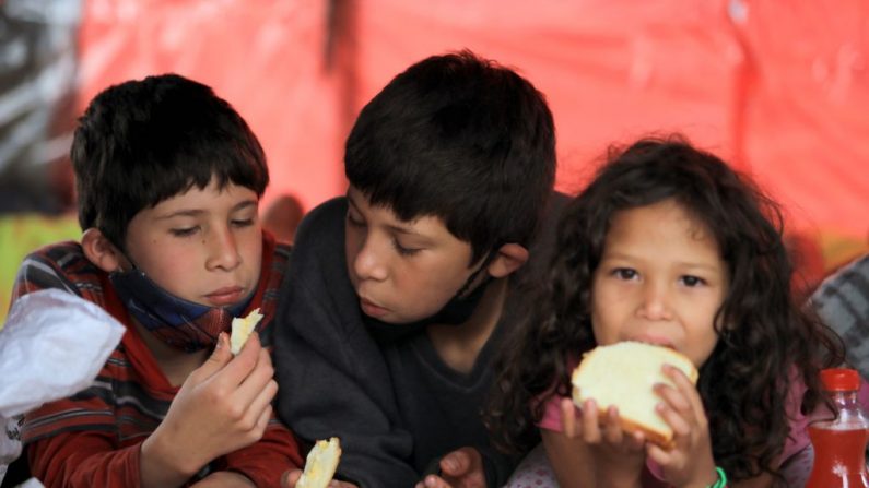 Niños comen pan en un campamento improvisado donde permanecen los migrantes venezolanos sin empleo y sin hogar durante la pandemia del coronavirus COVID-19 el 17 de junio de 2020.   (DANIEL MUNOZ/AFP vía Getty Images)