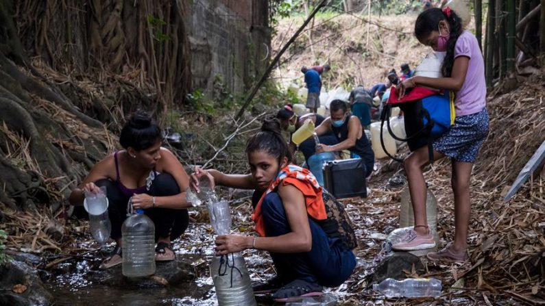 Fotografía del 26 de mayo de 2020 donde se observa a un grupo de personas recolectando agua en un riachuelo, en Caracas (Venezuela).  EFE/Miguel Gutiérrez
